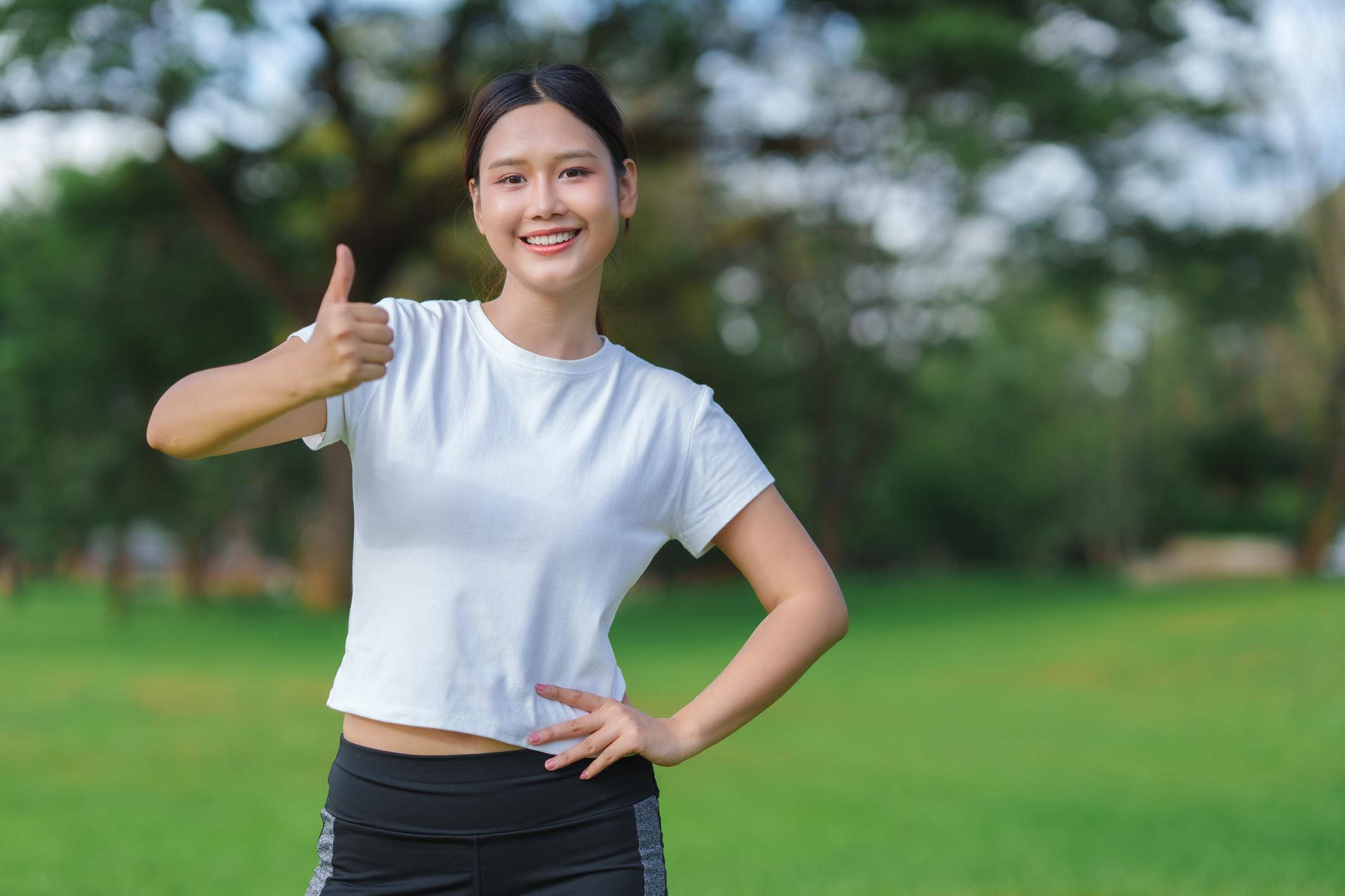Happy asian woman showing approval with thumbs up, expressing achievement, success, or excellent service outdoors