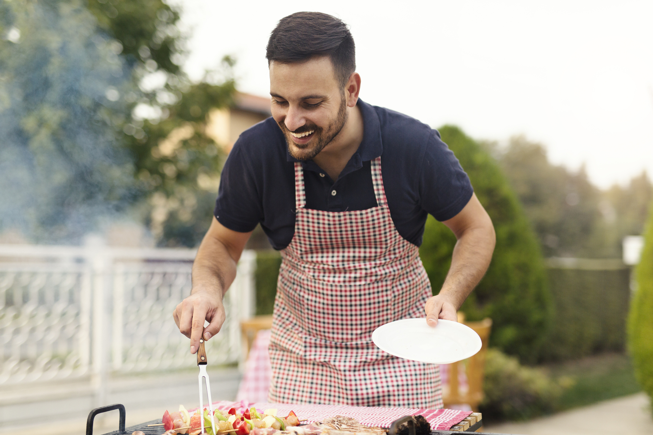 Young man preparing meat and vegetables on the grill